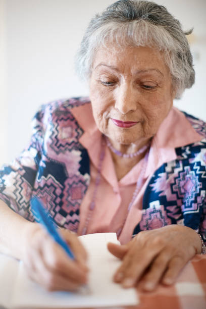 istock Senior woman looks down, concentrating on writing in notebook 1067337892