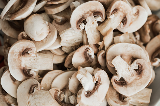White mushrooms cut in thin slices, close up, shot from above