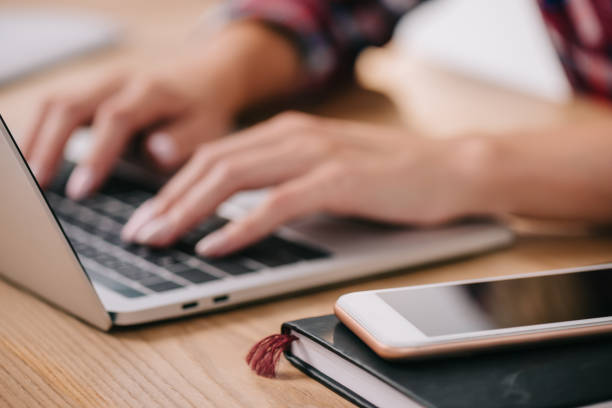 istock partial view of woman typing on laptop at tabletop with smartphone and notebook 1067343674