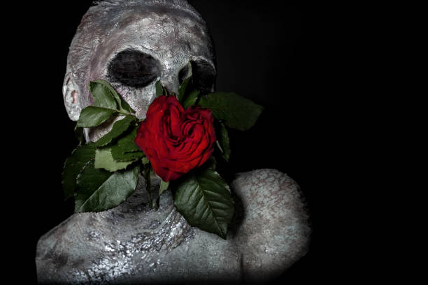 портрет девушки в серебряном макияже, глиняная маска.во рту держит бутон цветка розы - women halloween statue gray fotografías e imágenes de stock
