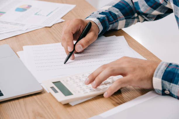 istock partial view of businessman making calculations at workplace with documents and laptop 1067349134