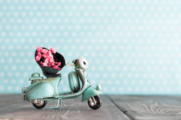 Tiny vintage toy blue mototrcycle with bunch of pink flowers stock photo