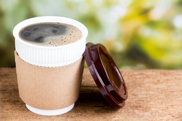 Coffee cup or disposable cup on the wooden table background on natural morning with copy space for your text and logo.
