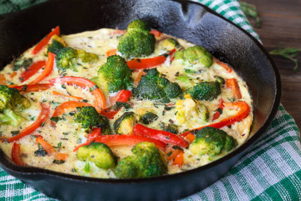 istock Frittata with broccoli and red pepper in iron skillet on rustic wooden background 1067354524