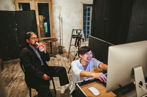 A photographer and his model are checking the photos on computer at photo studio.