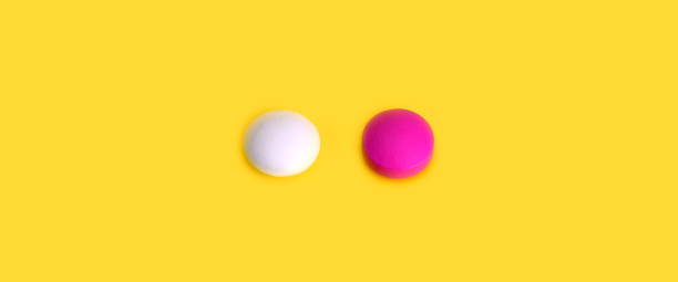 istock Two pills pink and white on a yellow background. View from above. 1067358316