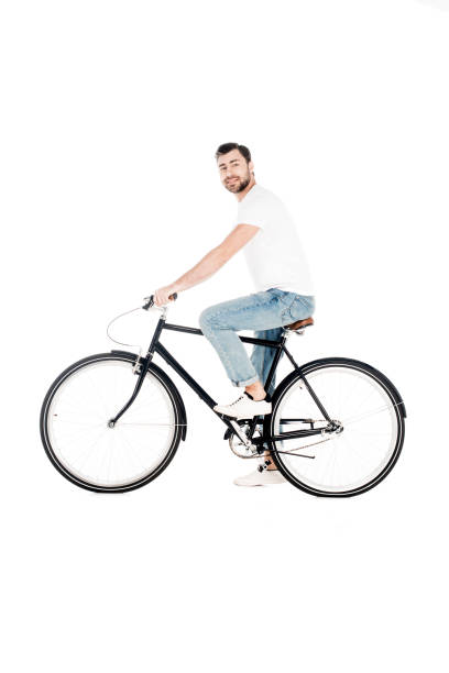 istock Handsome smiling young adult riding bicycle while looking at camera isolated on white 1067367088