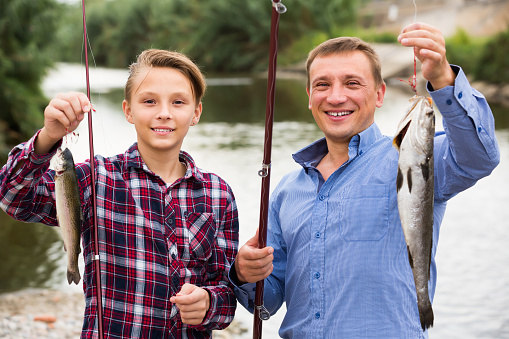 Photo of a two little boys and their parents spending quality time together while fishing on the riverbank
