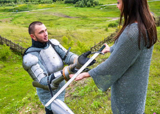 istock A lady in a chain mail hands a sword to her knight in armor. 1067380442