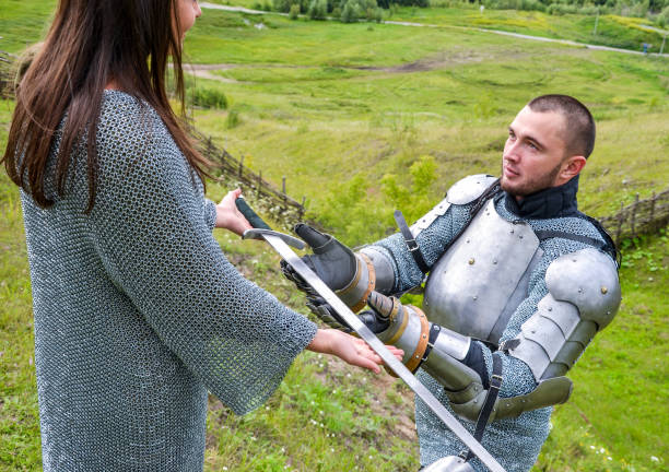 istock A lady in a chain mail hands a sword to her knight in armor. 1067380466