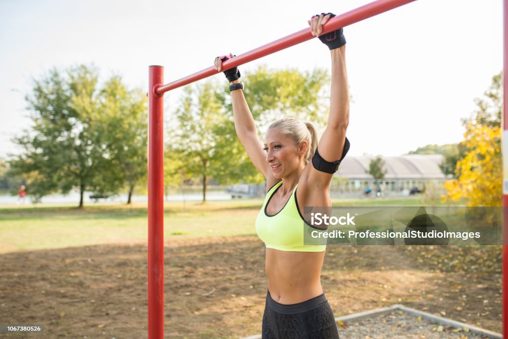 Workout time Attractive blonde sportswoman exercising on horizontal bar in the public park. Healthy lifestyle concept. 30-39 Years Stock Photo