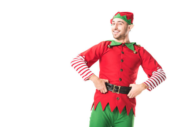 istock cheerful man in christmas elf costume looking at camera with hands on hips isolated on white 1067384158