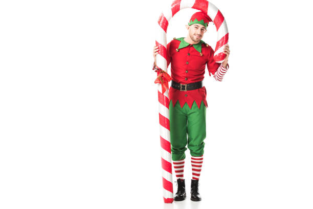 istock man in christmas elf costume standing under big candy cane isolated on white 1067384188