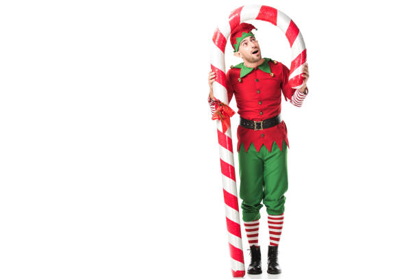 istock surprised man in christmas elf costume standing under big candy cane isolated on white 1067384214