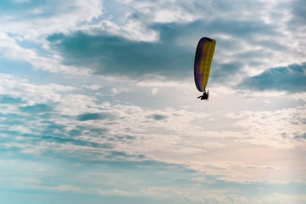 istock Motor paraglider flying in blue sky with white cloud in background. 1067391078