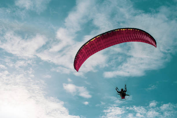 istock Motor paraglider flying in blue sky with white cloud in background. 1067393664