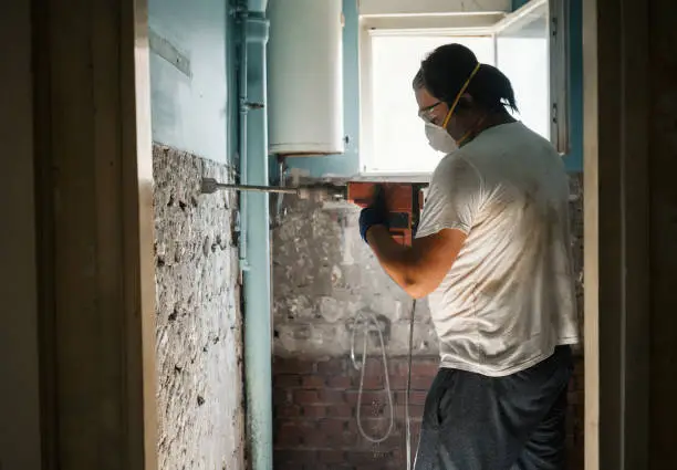 Men taking off old tile from wall with jackhammer