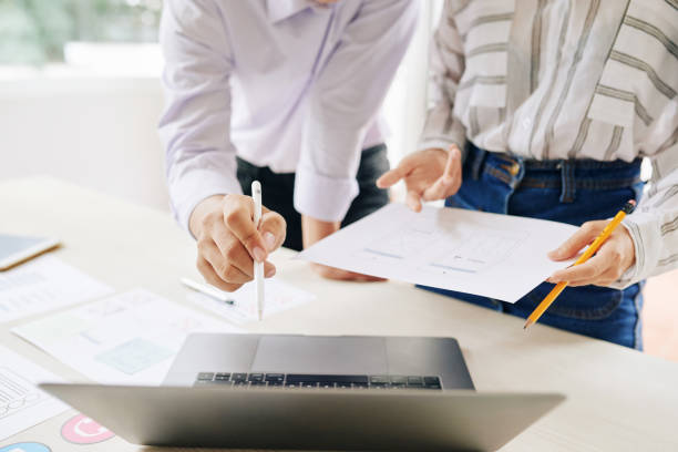 istock Crop colleagues with papers watching laptop 1067397540