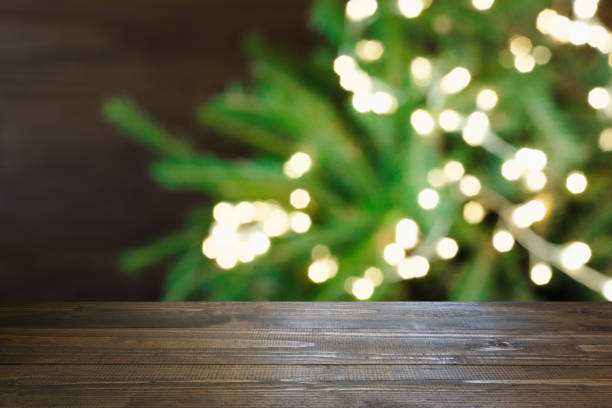 istock Wooden dark tabletop and blurred christmas tree bokeh. Xmas background for display your products. 1067400662