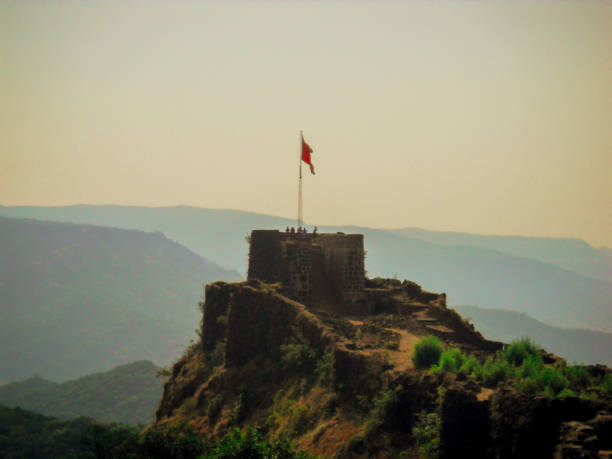 Pratapgad,An Ancient Fort in Maharashtra, India An saffron flag on Pratapgad an ancient fort in Maharashtra,India with ountains at Backdrop maharadja stock pictures, royalty-free photos & images