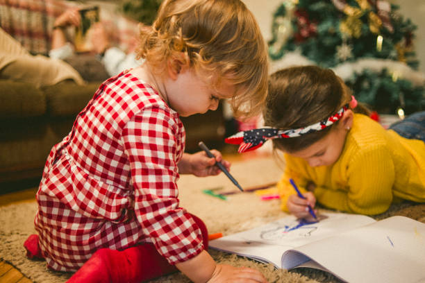 sisters drawing together at home on Christmas stock photo