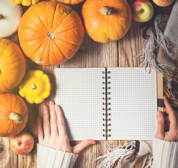 istock Womans hands on the notebook and pumpkins on wood background 1067414288
