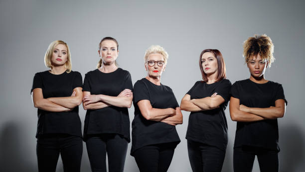 Group of confident women protesting Group of displeased women wearing black clothes, standing with arms crossed against grey background. Studio shot. warrior person photos stock pictures, royalty-free photos & images