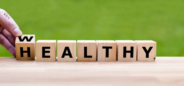 hand is turning a dice and changes the word "healthy" to "wealthy" - capital letter fotos imagens e fotografias de stock