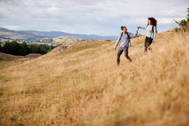 istock Mixed race young adult couple holding hands while walking walking down a hill during a mountain hike 1067423210