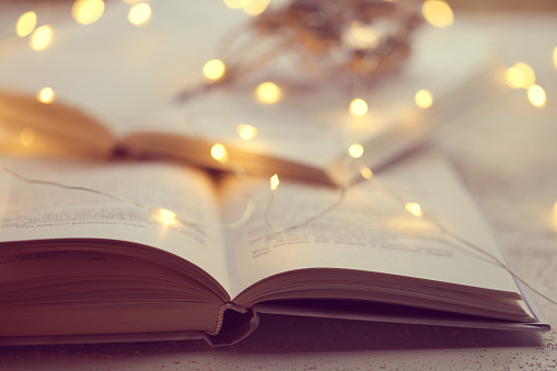 Winter books. Winter cozy reading.books close up. Book pages macro and shining garland soft focus.Cozy mood. Christmas books.