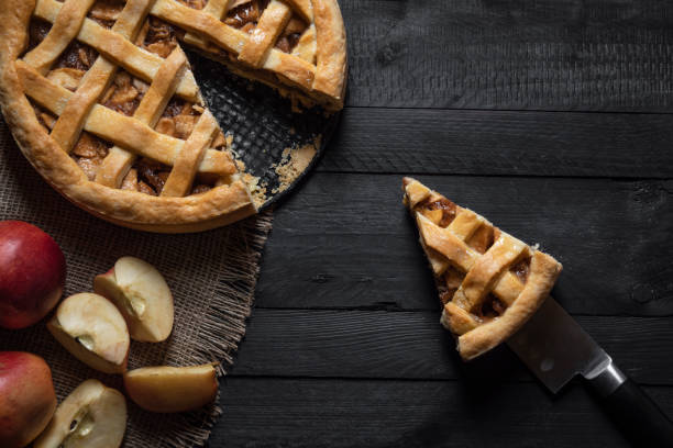 Kitchen table with an apple pie and a slice. Above view. Traditional sweet pie