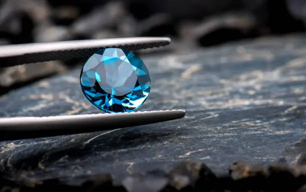 Blue topaz gemstone jewelry photo with black stone and dark lighting.