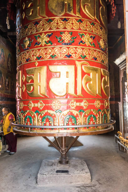Swayambunath Tample A woman stands next to a large prayer wheel of the temple of Boudhanath Stupa, Kathmandu, Nepal, Asia golden tample stock pictures, royalty-free photos & images
