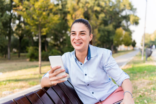 istock Pretty young sitting on a bench with mobile phone 1067435262