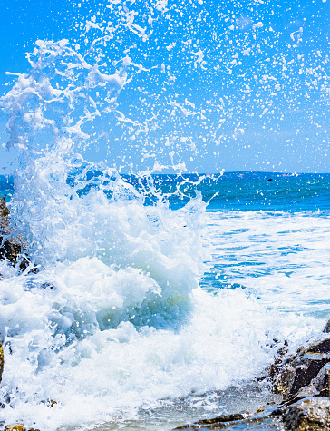 splashing waves crashing on the rocky shore at dawn sun