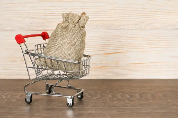 shopping cart with gift bag over wooden background, christmas concept