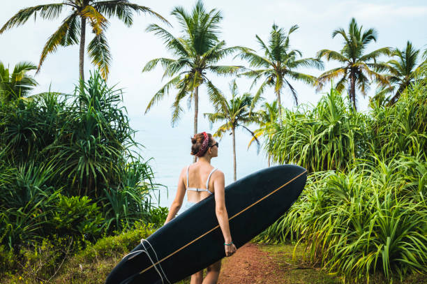 istock Female surfer carries longboard 1067444120