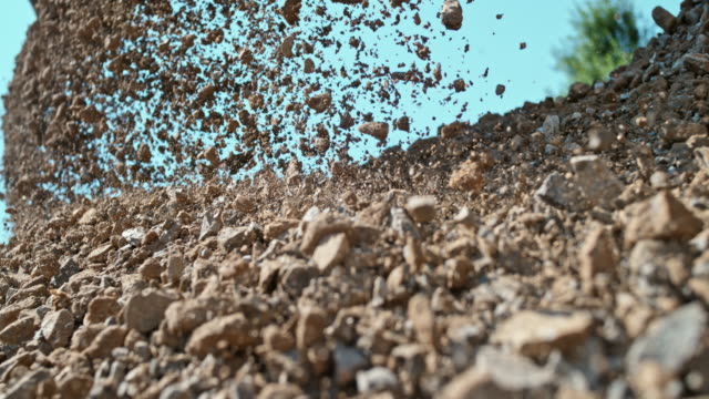 SLO MO Stones falling on a pile in sunshine