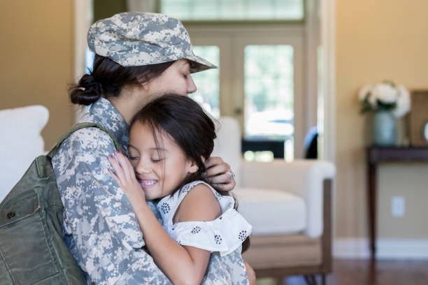 Young girl is happy to see army mom Relieved little girl hugs her mom after her mom's return home from military service. soldier family stock pictures, royalty-free photos & images