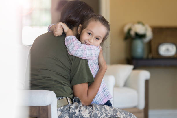 Little girl hugs her soldier mom Adorable little girl gives her mom a big hub upon her mom's return home from military service. proud army mom stock pictures, royalty-free photos & images