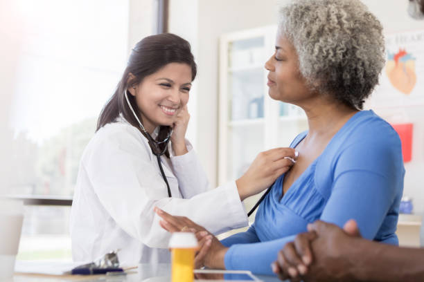 年配の女性の肺に耳を傾ける女性医師 - pill bottle pill stethoscope medical exam ストックフォトと画像