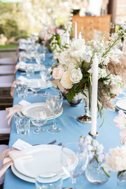 istock Festive table decorated with flowers and candles on a silver candlestick on blue tablecloth 1067449928