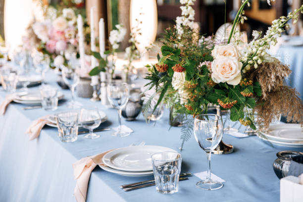 istock Festive table decorated with flowers and candles on a silver candlestick on blue tablecloth 1067450014