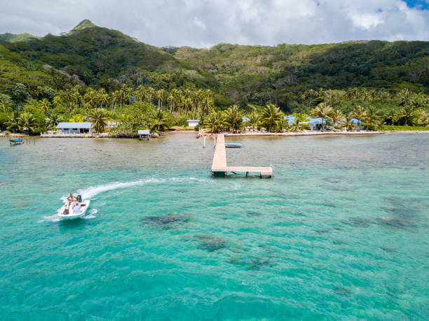 os turistas andando de jet barco de alta velocidade em uma deslumbrante azul azul ilha esmeralda de lagoa azul-turquesa, verde nas costas. raiatea, polinésia, oceania - french polynesia pier lagoon nautical vessel - fotografias e filmes do acervo