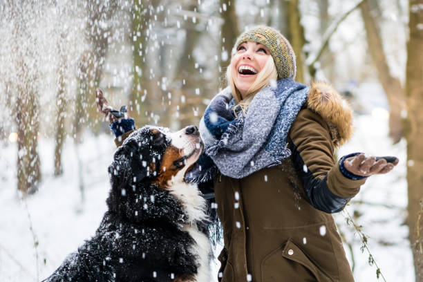 冬と彼女の犬の散歩の女性が一緒に雪を探る - snow hiking ストックフォトと画像