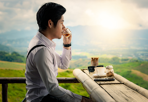 Men sit drinking tea and coffee with nature tranquil scene, relax looking at view on top of hill