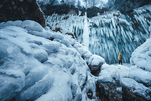 Man in yellow jacket watching a spectacular frozen waterfall (Pericnik, Slovenia).