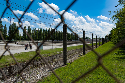 Visitors walk along the wire fence of the Dachau Concentration Camp near Munich in Germany on June 3, 2018