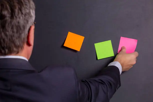 A person creates a new model or story. Businessman glues a colored sticker with a new idea.