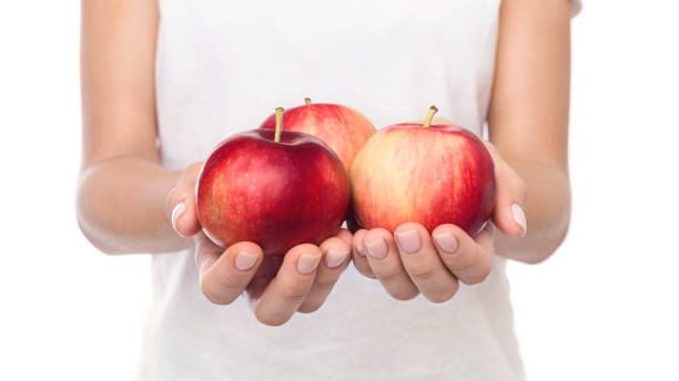 istock Three ripe apples in female hands over white background 1067483412